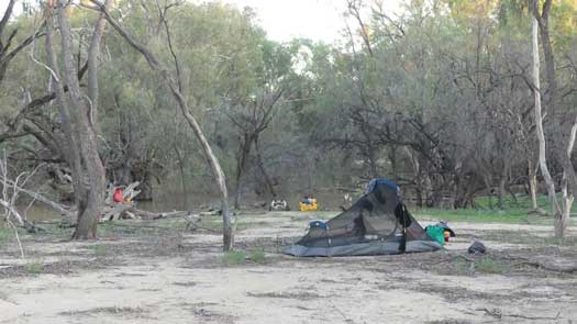 Camping by river with tent, kayak, gear and water purification setup