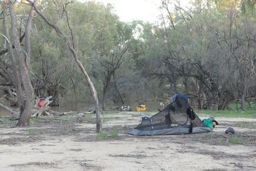 Camping by river with tent, kayak, gear and water purification setup