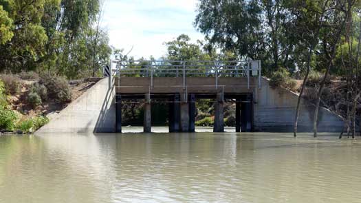 Water being released from gates on small dirt dam wall