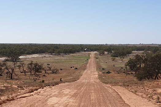 Long dirt road with a building in the distance