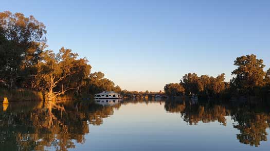 Wide river with houseboats and a bridge