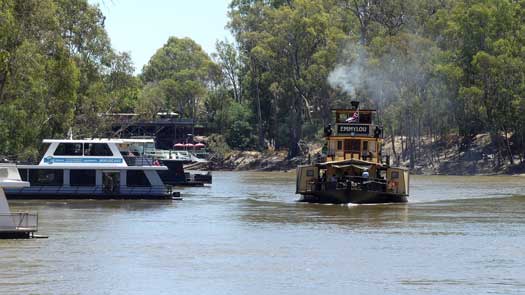 Paddle boat on the river and houseboats moored to the shoreline