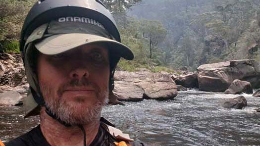 Man in front of some large rocks in the river