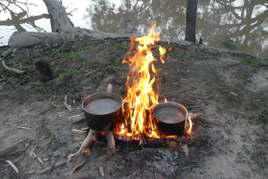Pots heating water on a campfire